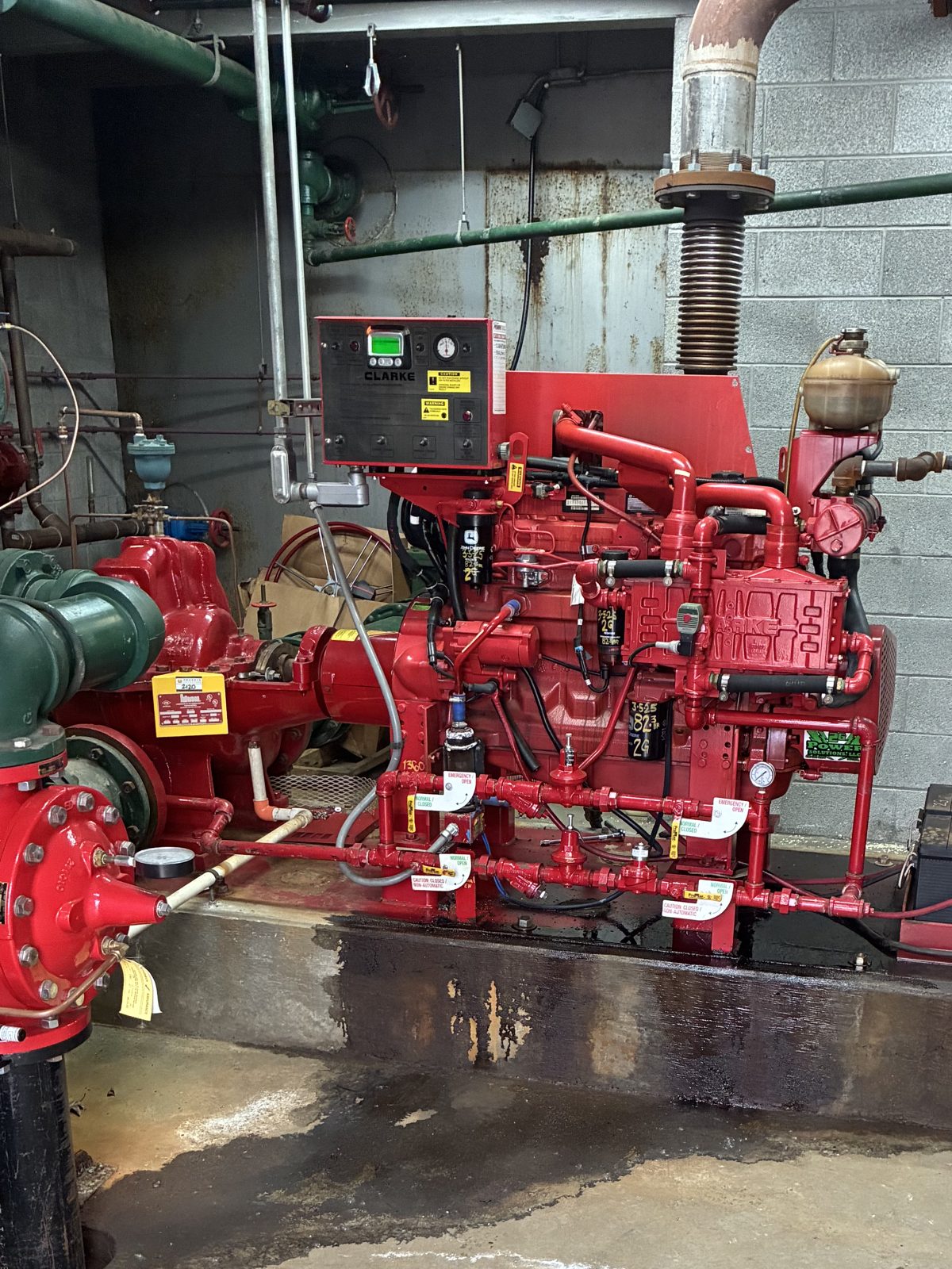 Red diesel fire pump unit and controller in a commercial fire pump room, serviced by 2G Power Solutions