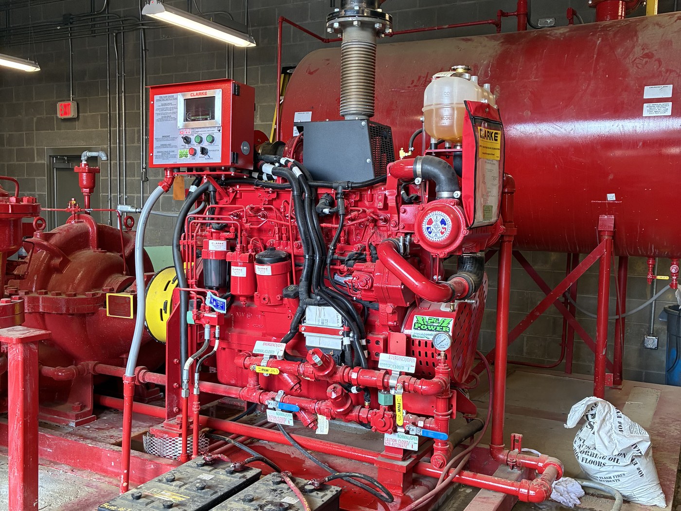 A red Clarke diesel fire pump engine and controller in a fire pump room, serviced by 2G Power Solutions