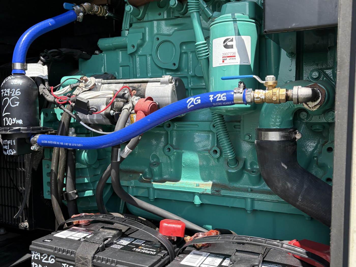 A 2G Power Solutions technician performing hands-on service on a commercial standby generator engine