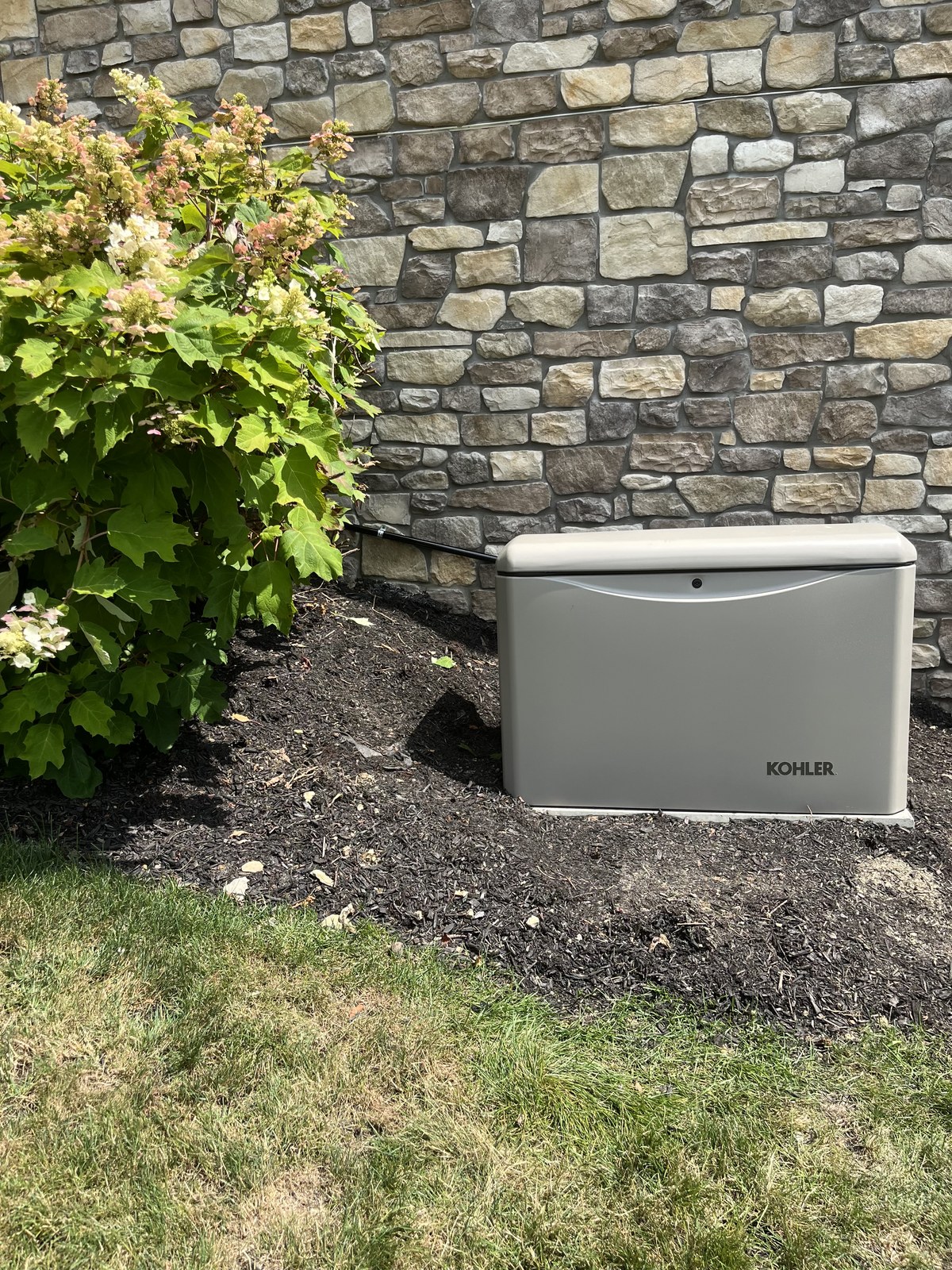 Kohler home standby generator installed beside a stone-veneer home by 2G Power Solutions